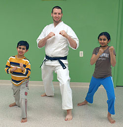 Two children and an adult in a karate pose.
